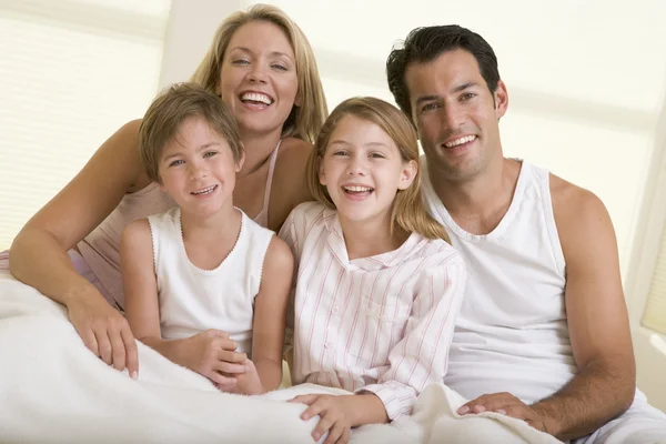 Familia sentada en la cama sonriendo —  Fotos de Stock