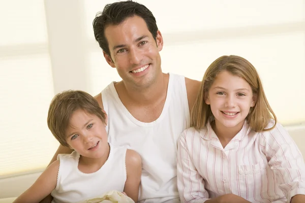 Man med två små barn sitter i sängen leende — Stockfoto