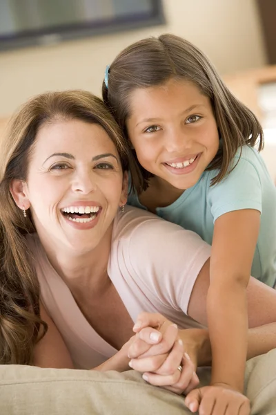 Vrouw en jonge meisje in woonkamer glimlachen — Stockfoto