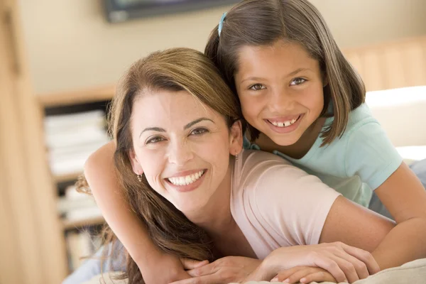 Vrouw en jonge meisje in woonkamer glimlachen — Stockfoto
