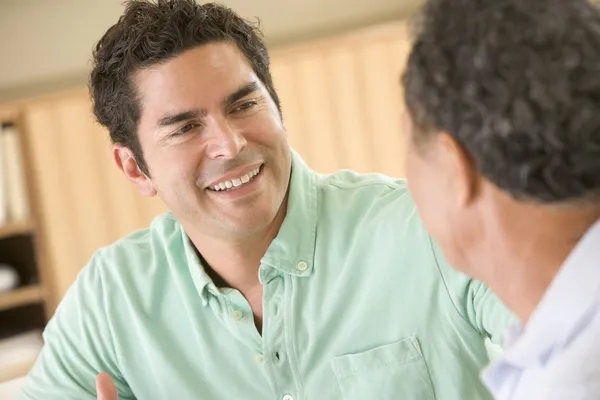 Twee mannen zitten in woonkamer praten en glimlachen — Stockfoto