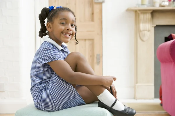 Young girl in front hallway fixing shoe and smiling — Stock Photo, Image