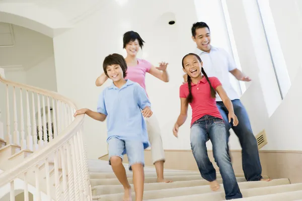 Family running down staircase smiling — Stock Photo, Image