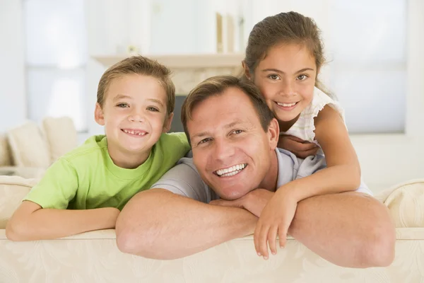 Man och två barn sitter i vardagsrummet leende — Stockfoto