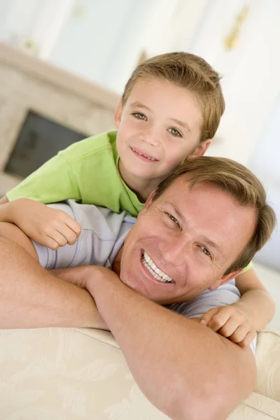 リビング ルームの笑みを浮かべて座っている男と若い少年 — ストック写真