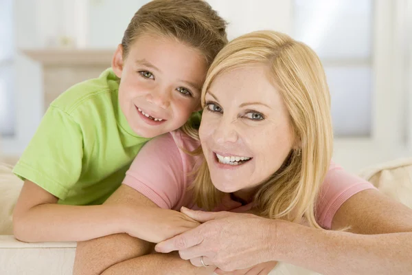 Vrouw en jonge jongen zitten in de woonkamer glimlachen — Stockfoto
