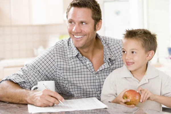 Homem e menino na cozinha com jornal de maçã e café smi — Fotografia de Stock