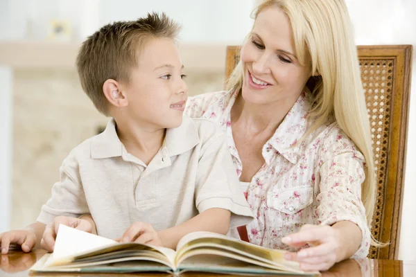 Жінка і молодий хлопчик читає книгу в їдальні посміхаючись — стокове фото