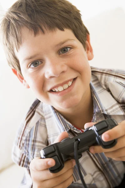 Jovem menino segurando controlador de jogo de vídeo sorrindo — Fotografia de Stock