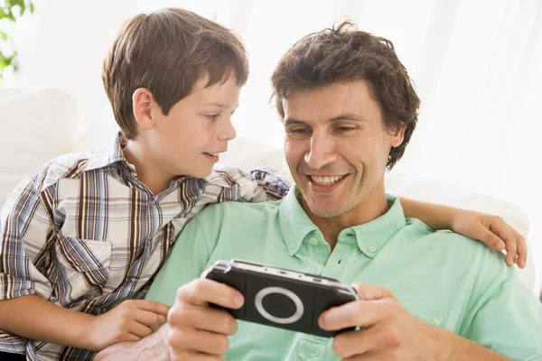 Man en jonge jongen met handheld game glimlachen — Stockfoto