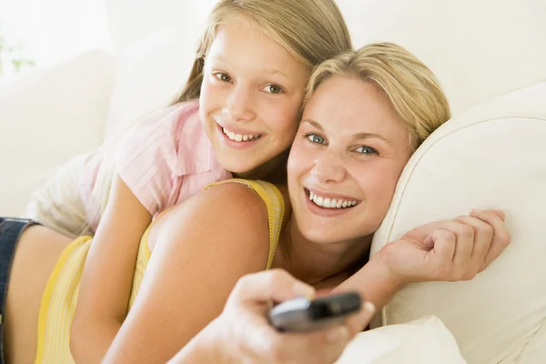Frau und junges Mädchen mit Fernbedienung umarmen sich auf dem Sofa lächelnd — Stockfoto