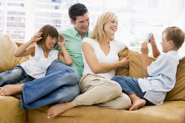 Семья, сидящая в гостиной с улыбающейся цифровой камерой — стоковое фото