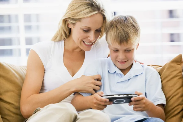 Frau und kleiner Junge im Wohnzimmer mit Handheld-Videospiel lächeln — Stockfoto