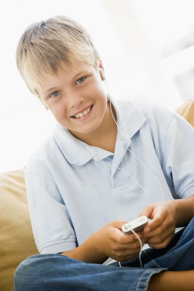 Niño en la sala de estar con reproductor de MP3 sonriendo — Foto de Stock