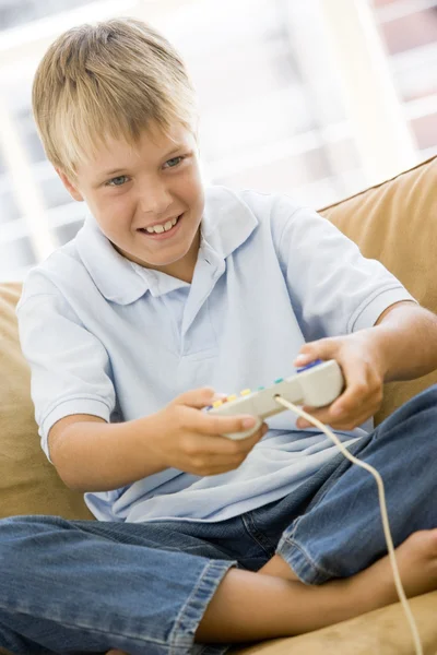 Niño en la sala de estar con controlador de videojuegos sonriendo — Foto de Stock