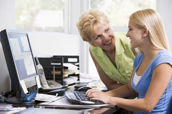Mujer y niña en la oficina en casa con la computadora sonriendo —  Fotos de Stock