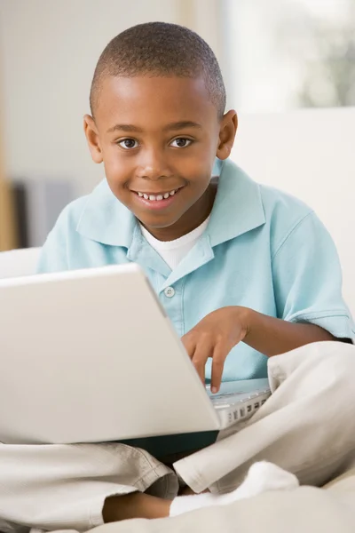 Ung pojke i vardagsrum med laptop leende — Stockfoto