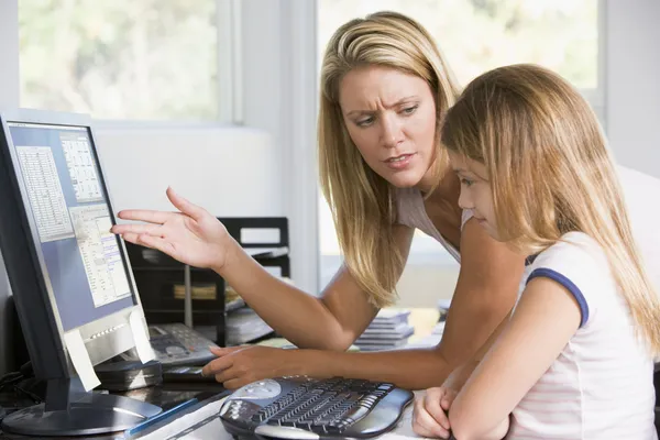 Mujer y chica joven en la oficina en casa con la computadora mirando infeliz —  Fotos de Stock
