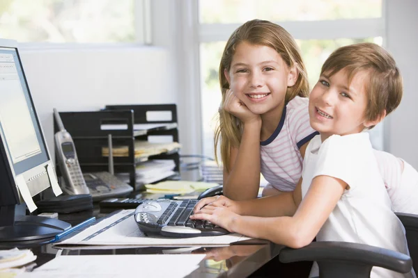 Young boy and young girl in home office with computer smiling — Stock Photo, Image