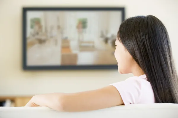 Νεαρό κορίτσι στο καθιστικό με τηλεόραση επίπεδης οθόνης — Φωτογραφία Αρχείου