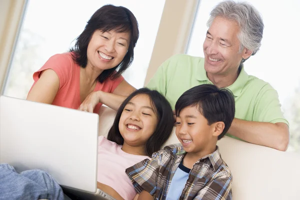 Met twee jonge kinderen in woonkamer met laptop smilin (echt) paar — Stockfoto