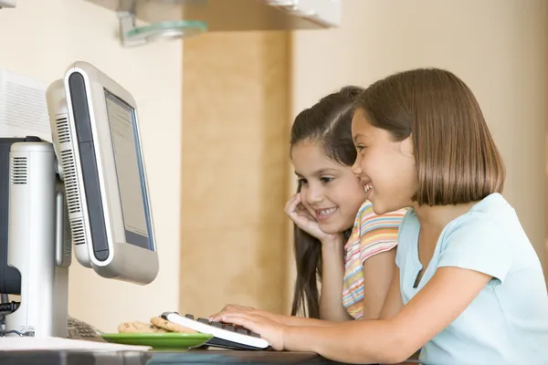 Iki Genç Kız Gülümseyerek Bilgisayar Ile Mutfakta — Stok fotoğraf