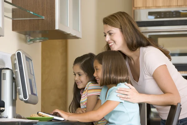 女人和两个年轻女孩在厨房里与计算机微笑 — 图库照片