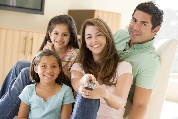 Семья в гостиной с пультом дистанционного управления улыбается — стоковое фото