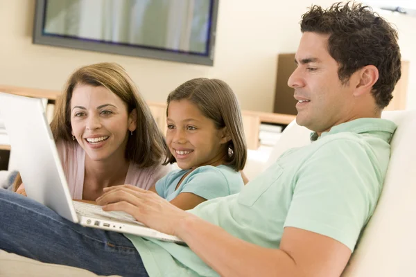 Família na sala de estar com laptop sorrindo — Fotografia de Stock