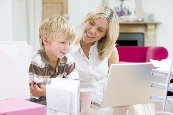 家庭办公室与笔记本电脑微笑的女人和年轻男孩 — 图库照片