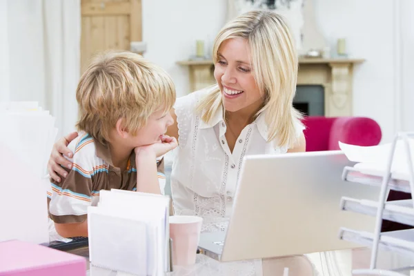 家庭办公室与笔记本电脑微笑的女人和年轻男孩 — 图库照片