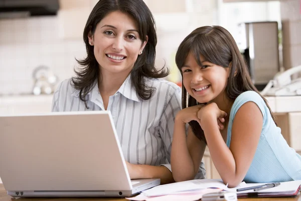 Kvinna och unga flickan i köket med laptop och pappersarbete smilin — Stockfoto
