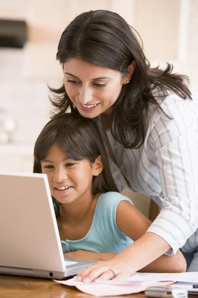 Mulher e menina na cozinha com laptop e papelada sorridente — Fotografia de Stock