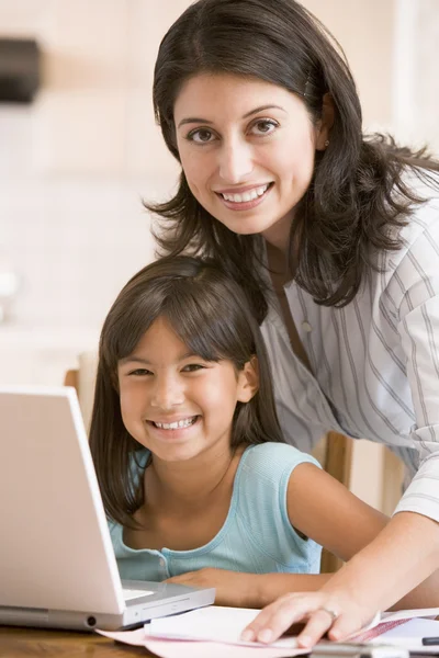 Mujer y niña en la cocina con laptop y papeleo smilin —  Fotos de Stock