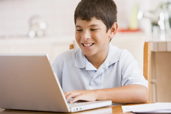 ノート パソコンと書類の笑顔とキッチンで若い男の子 — ストック写真