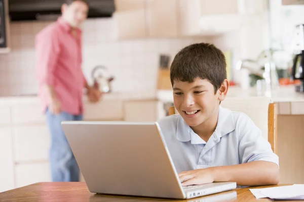 厨房用笔记本电脑和文书工作和男人在一起微笑的年轻男孩 — 图库照片