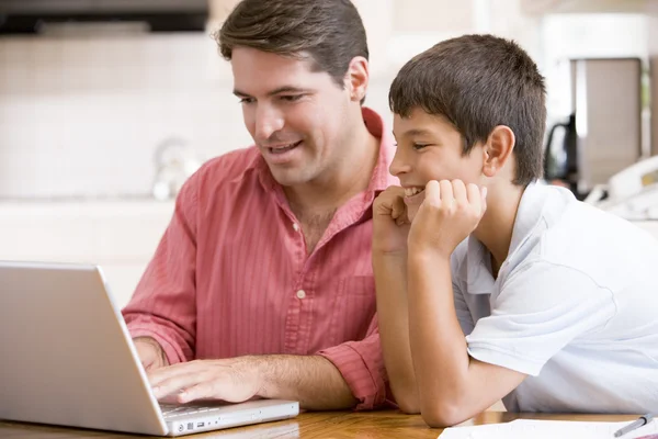 Мужчина помогает мальчику на кухне с улыбающимся ноутбуком — стоковое фото