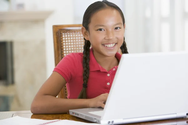 带手提电脑在饭厅微笑的小女孩 — 图库照片