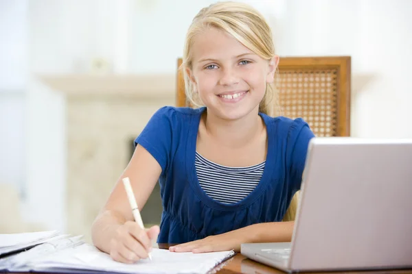 Chica joven con portátil haciendo la tarea en el comedor sonriendo —  Fotos de Stock