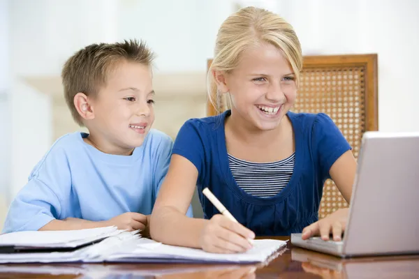 Двое маленьких детей с ноутбуком делают домашнюю работу в столовой smi — стоковое фото