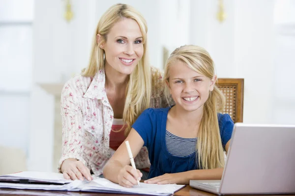 Vrouw helpen jong meisje met laptop doen huiswerk in eetkamer — Stockfoto