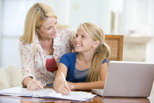 Женщина помогает девушке с ноутбуком делать домашнее задание в столовой — стоковое фото