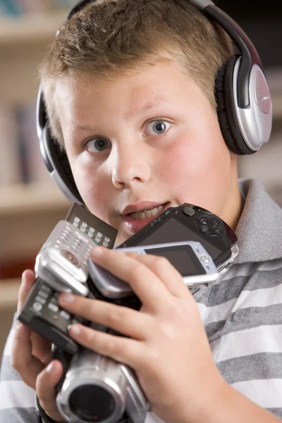 Мальчик в наушниках в спальне держит много электроники — стоковое фото