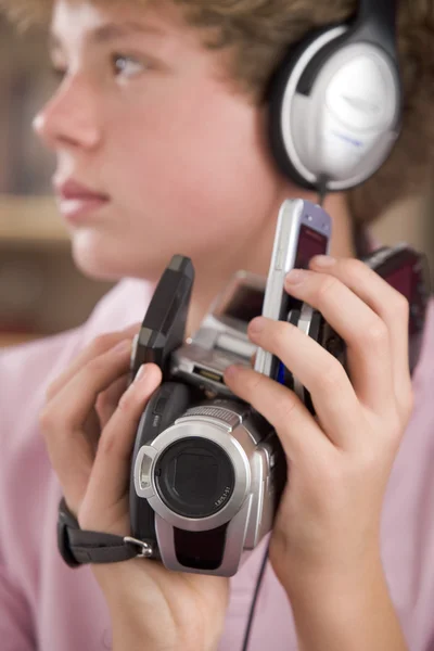 Joven Niño Usando Auriculares Dormitorio Sosteniendo Muchos Electrónicos —  Fotos de Stock