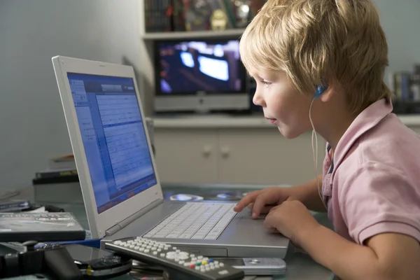 小男孩在卧室使用的便携式计算机和听 Mp3 播放器 — 图库照片