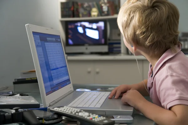 小男孩在卧室使用的便携式计算机和听 Mp3 播放器 — 图库照片