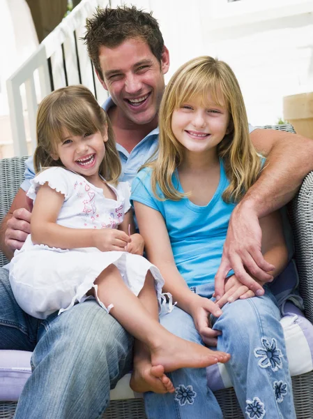 남자와 두 어린 소녀의 미소를 패티 오에 앉아 — 스톡 사진