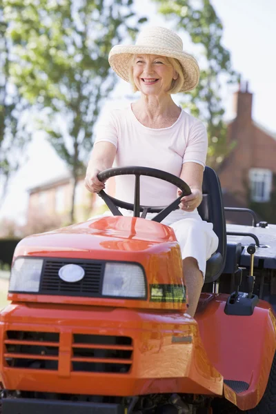 Vrouw buiten rijden grasmaaier glimlachen — Stockfoto