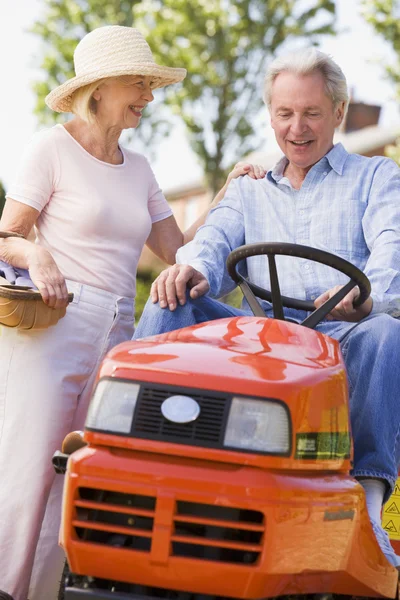 Couple outdoors with tools and lawnmower smiling — Stock Photo, Image