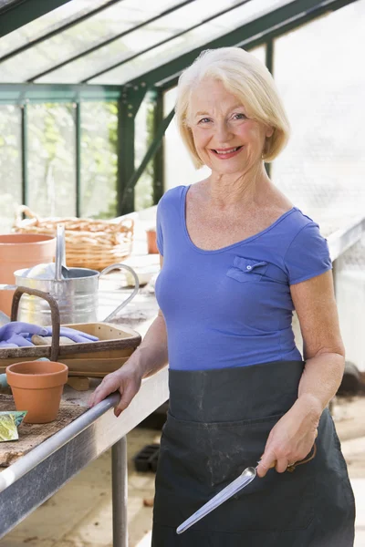 Kvinna i växthuset hålla spade och leende — Stockfoto